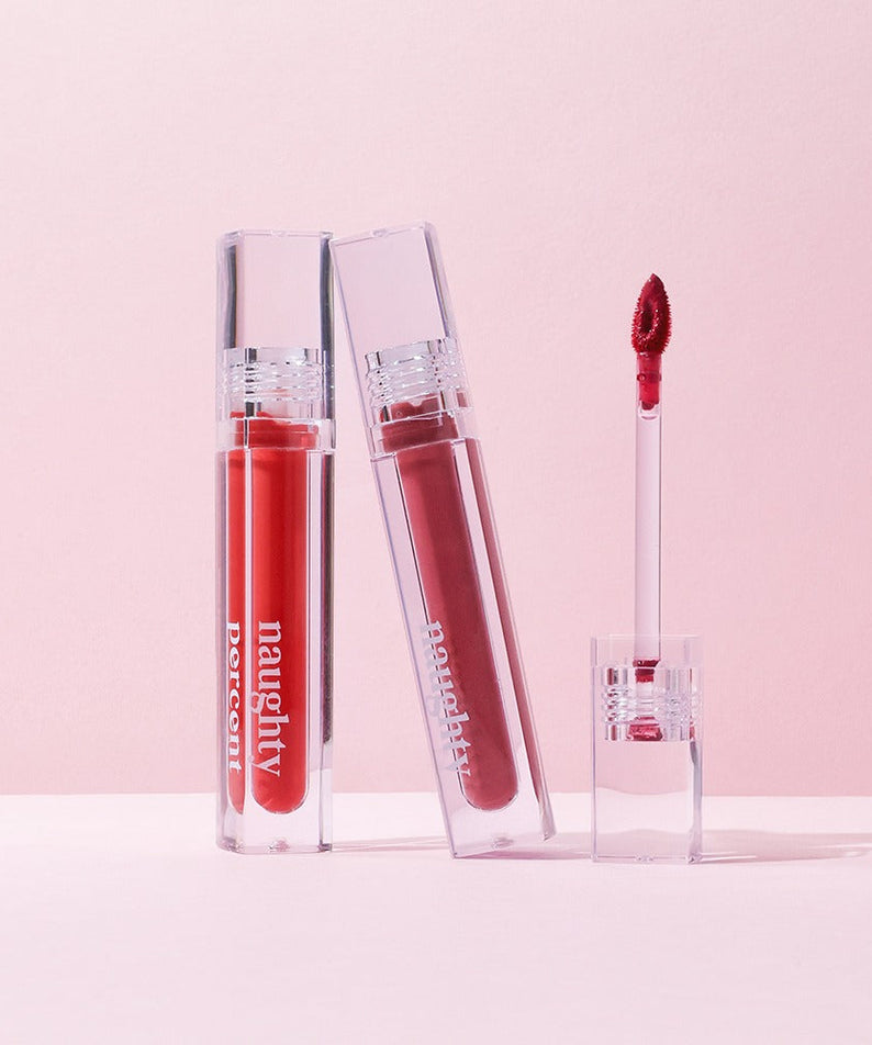 NAUGHTY PERCENT Matte Bloom Tint in two open transparent tubes on a light pink background.