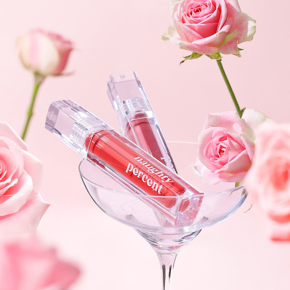 NAUGHTY PERCENT Matte Bloom Tint product displayed with pink roses in a glass, showcasing vibrant color and elegant packaging.
