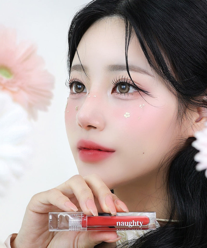Woman holding NAUGHTY PERCENT Matte Bloom Tint with floral background