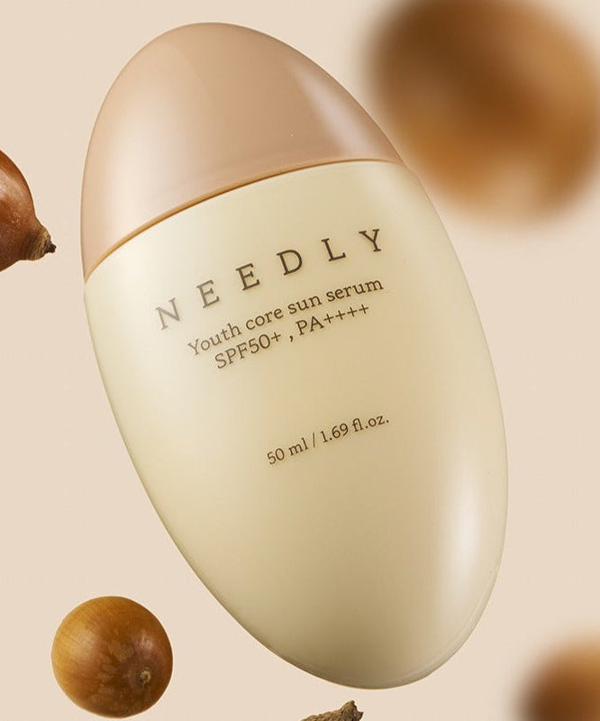 NEEDLY Youth Core Sun Serum 50ml bottle with SPF 50+ and PA++++, surrounded by natural elements. Ideal for skincare protection.