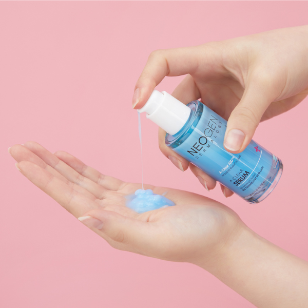 Applying NEOGEN A Clear Serum 30ml from bottle into hand against pink background