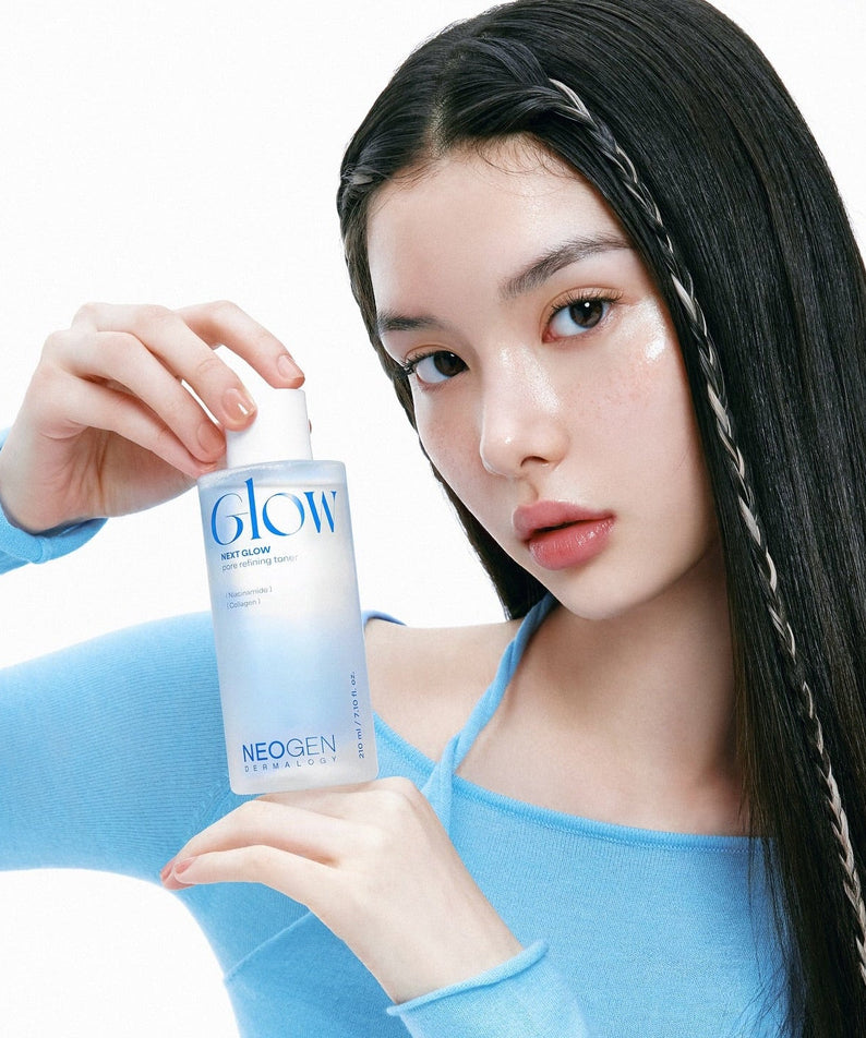 Person holding NEOGEN Next Glow Pore Refining Toner 210ml demonstrating skincare application in blue attire.