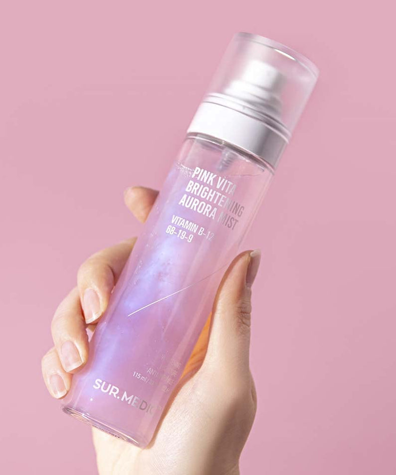 Hand holding NEOGEN Pink Vita Aurora Mist 115ml against a pink background