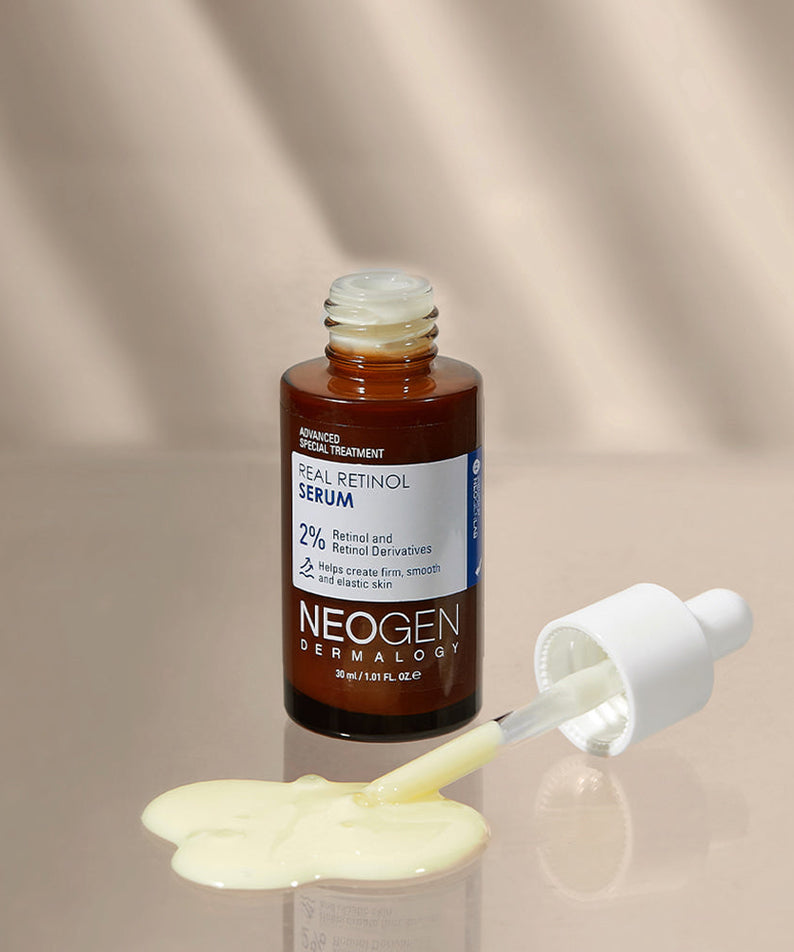 NEOGEN Real Retinol Serum 30ml with dropper and spilled serum on beige background.