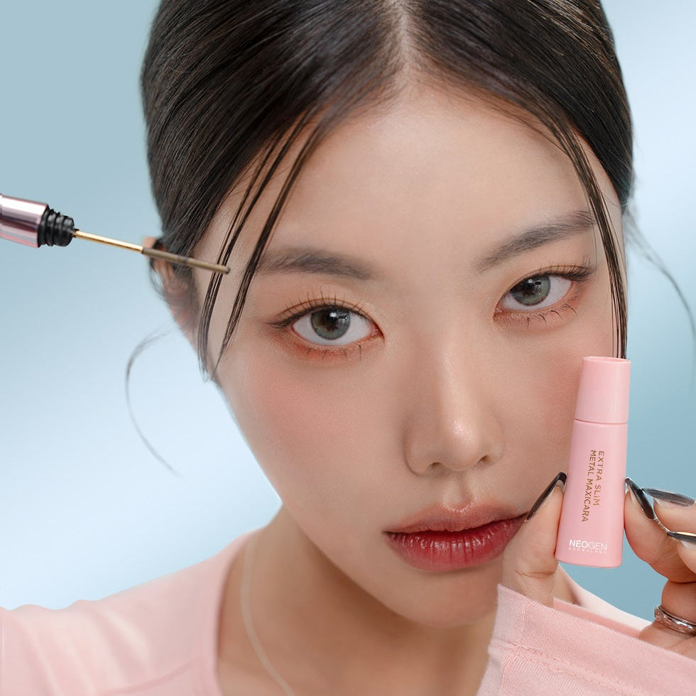 Woman applies NEOGEN Slim Metal Mascara 6ml for enhanced eyelashes, showcasing precise application.