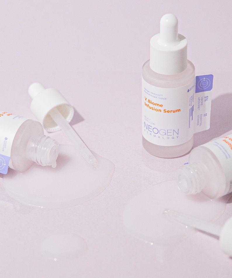 Bottles of NEOGEN V Biome Infusion Serum 30ml with droppers and serum spillage on a pastel surface.