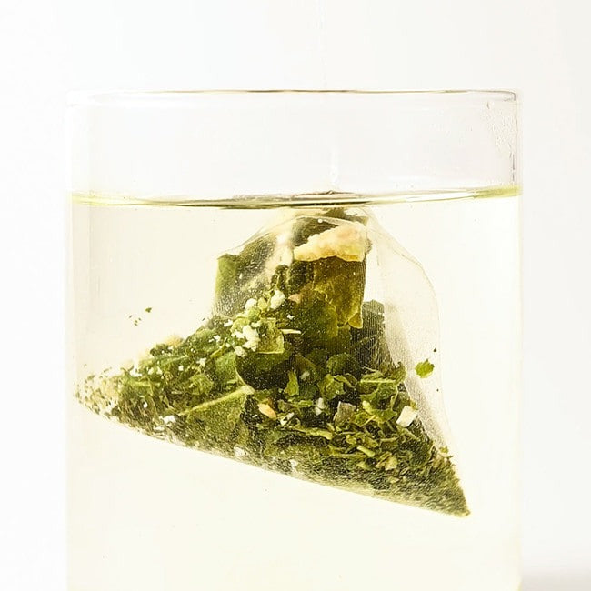 Glass of brewed NOTHING BETTER Luv Tea Lemon Green Tea (X15) with visible green tea bag inside.