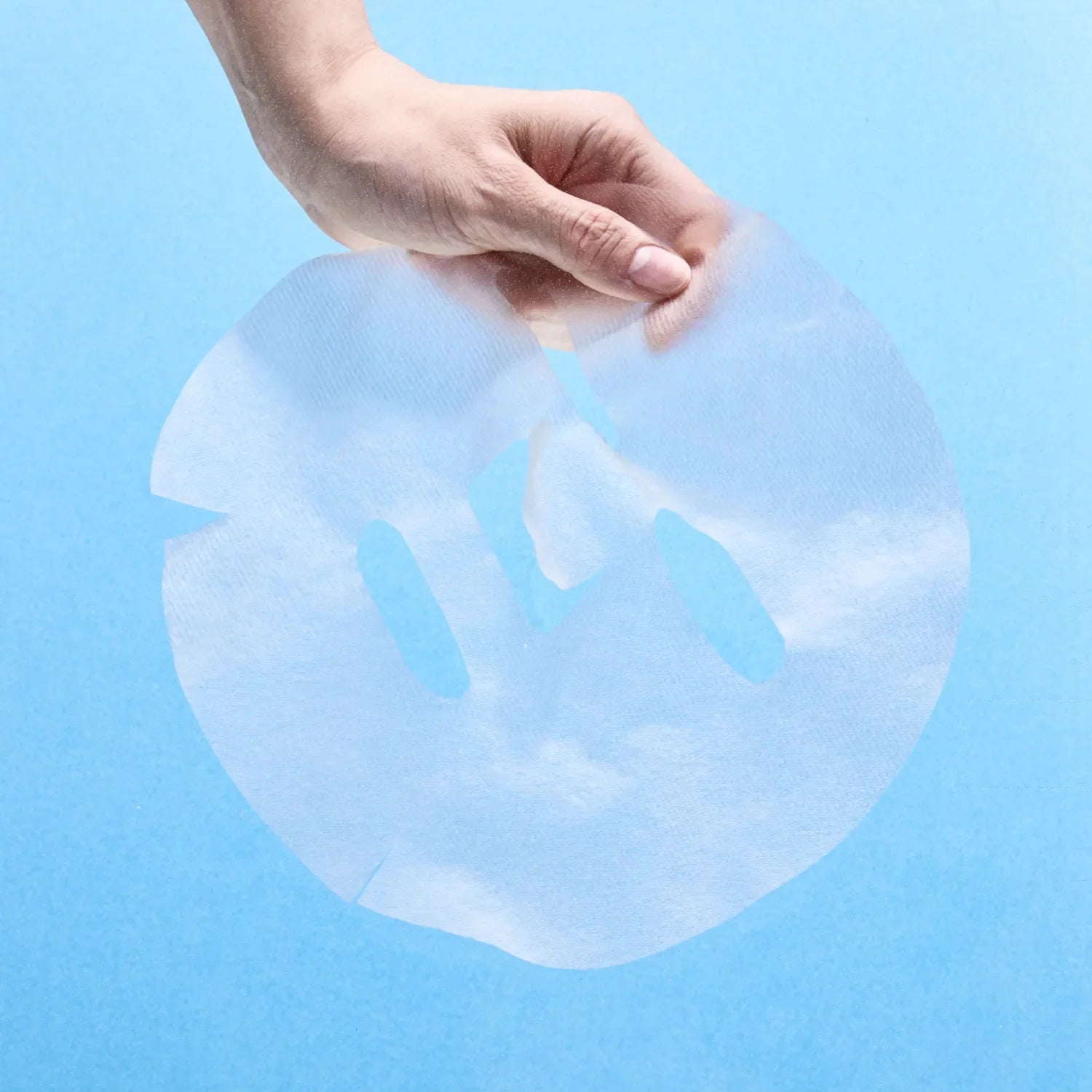 Hand holding NUMBUZIN No.1 Hyaluronic Panthenic Acid Clear Soothing Gauze Pack sheet against blue background.