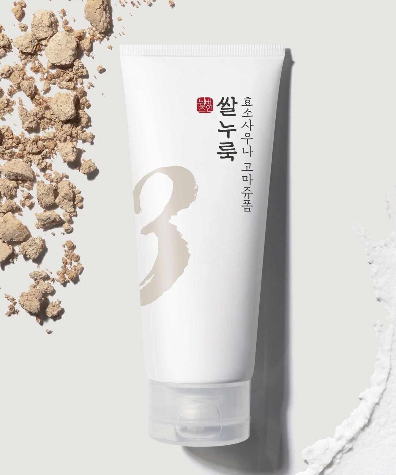 NUMBUZIN No.3 Rice Yeast Enzyme Suana Gommage Foam 170ml with textured background of rice and enzyme powder on a gray surface.