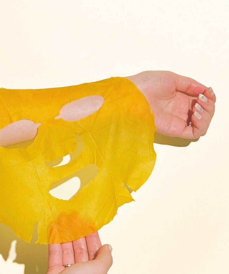 Hands holding NUMBUZIN No.5 Vitamin Spotlight Sheets Mask in yellow against a light background.