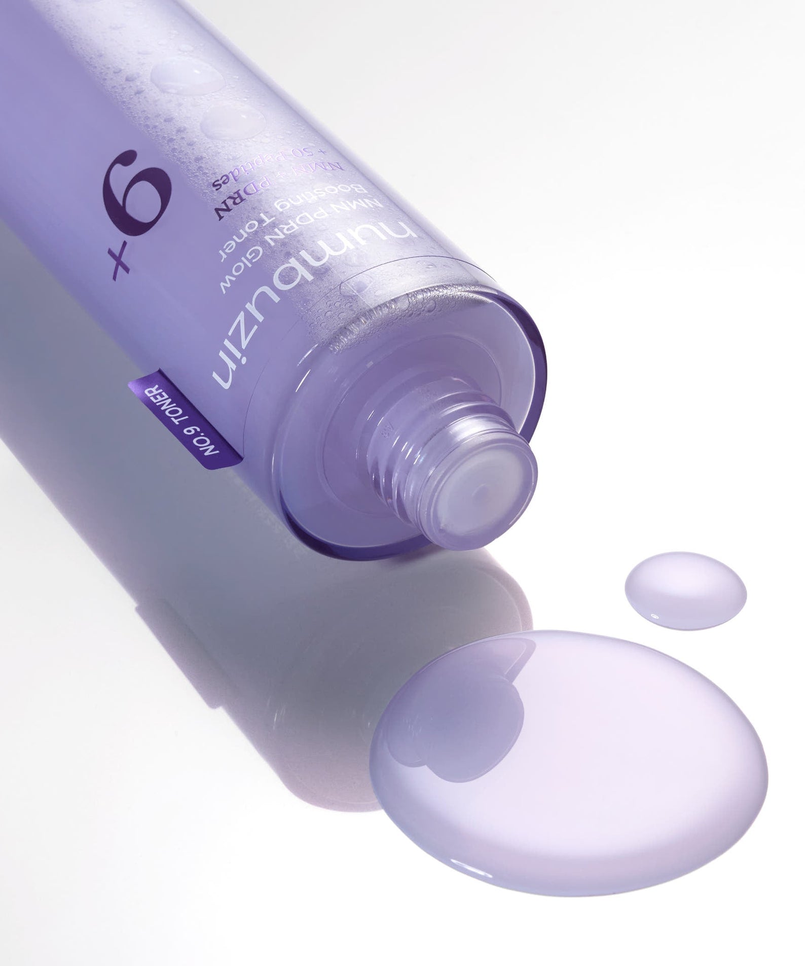 NUMBUZIN No.9 NMN PDRN Glow Boosting Toner 150ml bottle with spilled toner highlighting the product's texture and color