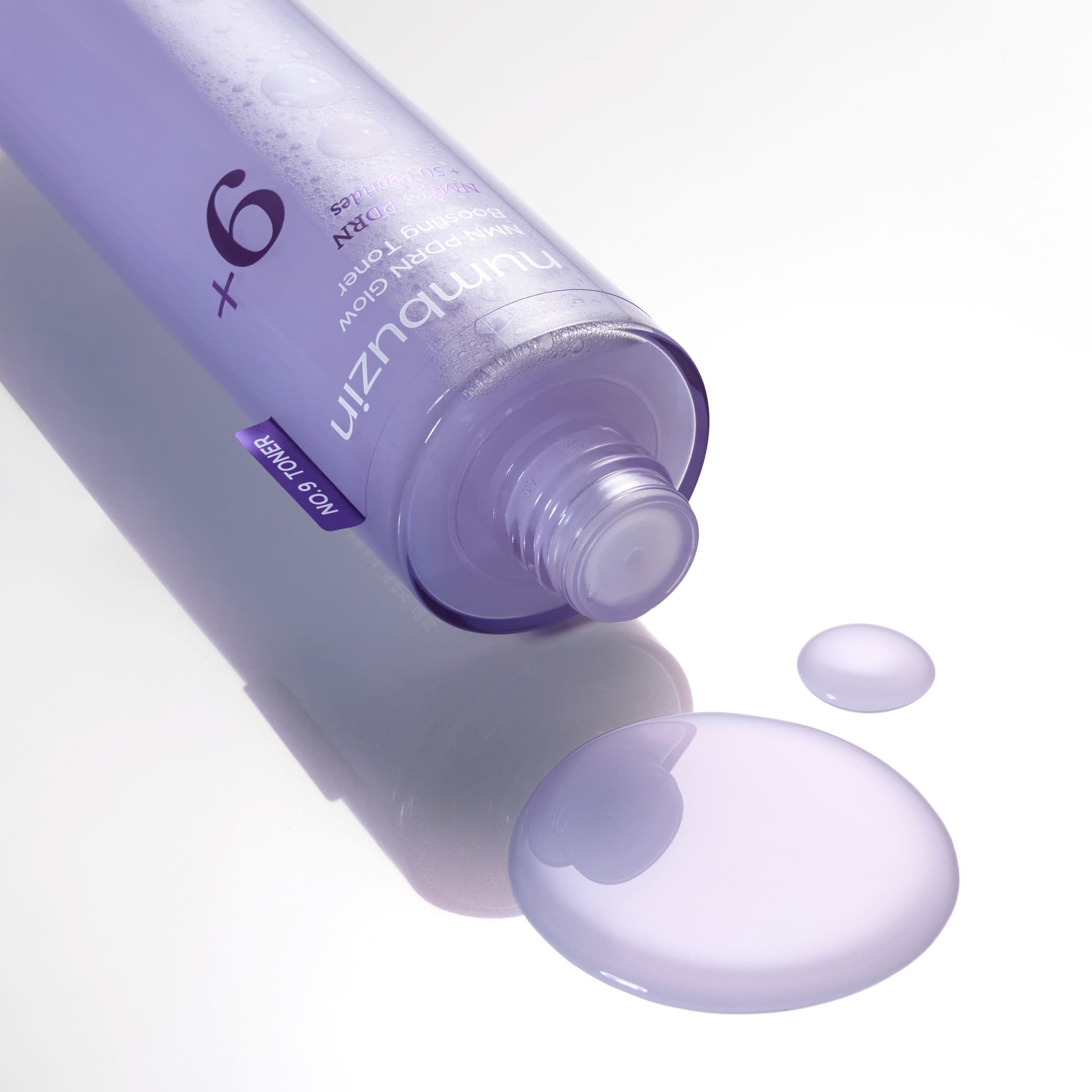 NUMBUZIN No.9 NMN PDRN Glow Boosting Toner 150ml bottle with spilled toner highlighting the product's texture and color