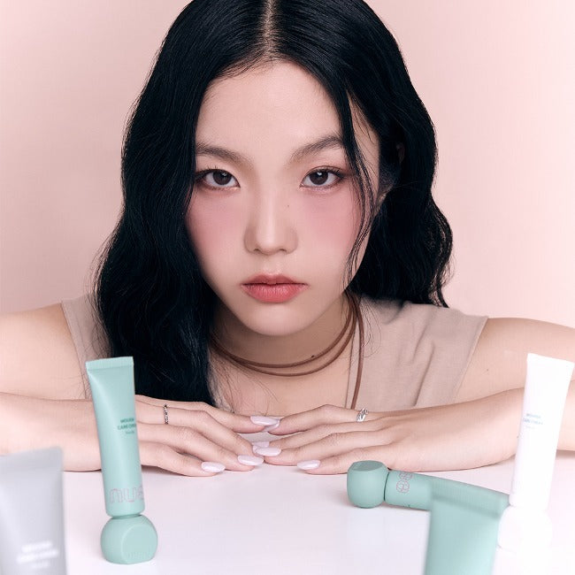 Woman showcasing NUSE Mousse Care Cheek Handy with makeup products on a table