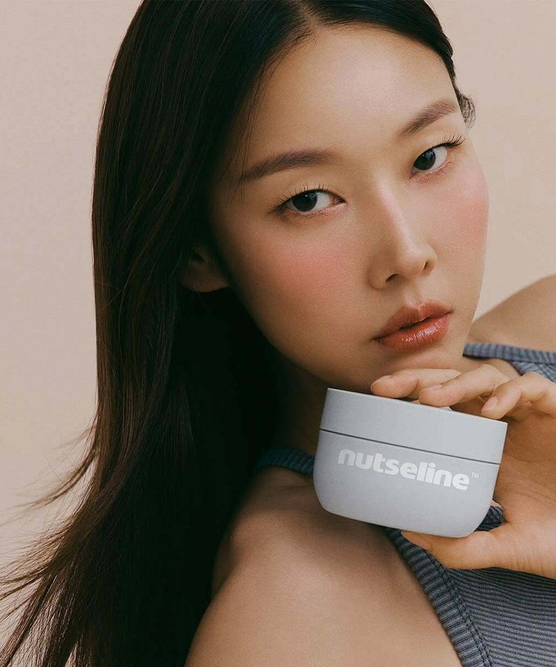 Woman holding NUTSELINE Aroma Nut Gray Body Scrub 200g container