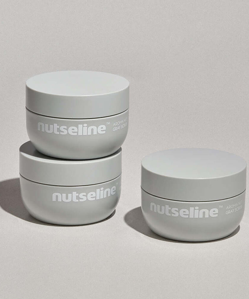 Three jars of NUTSELINE Aroma Nut Gray Body Scrub 200g stacked and displayed on a neutral background