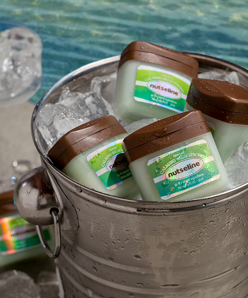 Ice bucket with NUTSELINE Cica Nut Calming Balm Strong 50ml jars placed by the poolside.