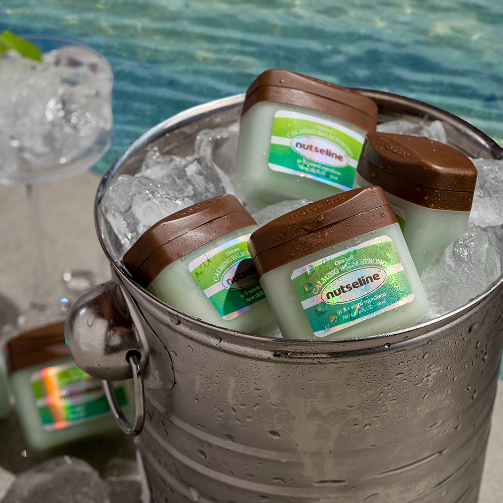 Ice bucket with NUTSELINE Cica Nut Calming Balm Strong 50ml jars placed by the poolside.