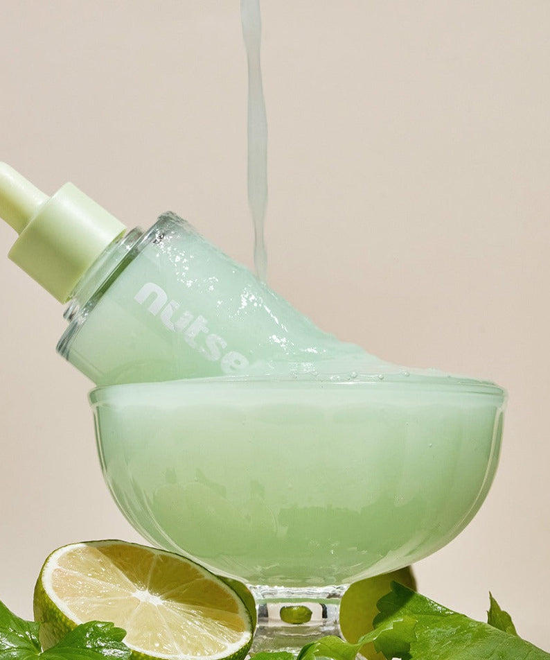 NUTSELINE Cica Nut Hyal Ampoule 90ml in decorative display with lime, showcasing product texture and natural ingredients.