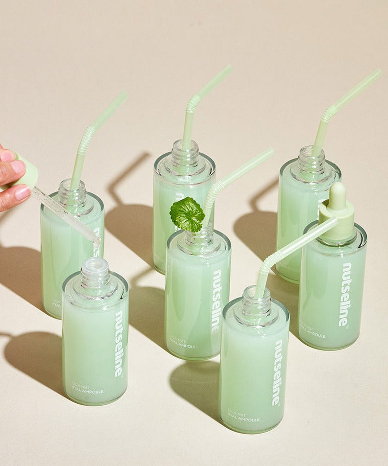 NUTSELINE Cica Nut Hyal Ampoule 90ml bottles with green liquid and pipette on a beige background.