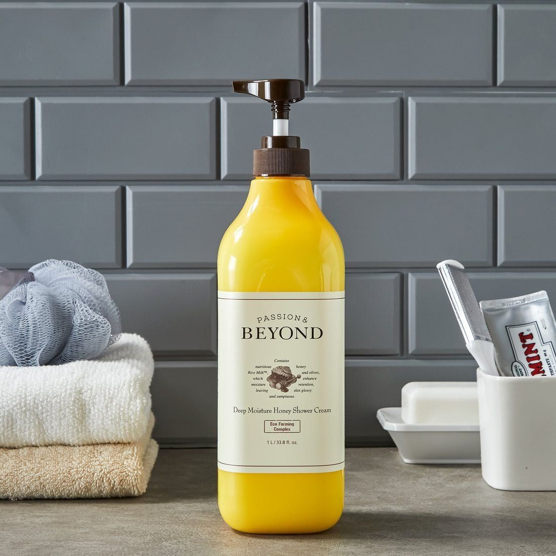 PASSON&BEYOND Deep Moisture Honey Shower 1L bottle on bathroom counter with towels and toothpaste