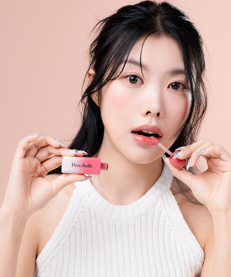 Woman applying PEACHOLIC Water Glow Lip Tint, showcasing vibrant color and hydration.
