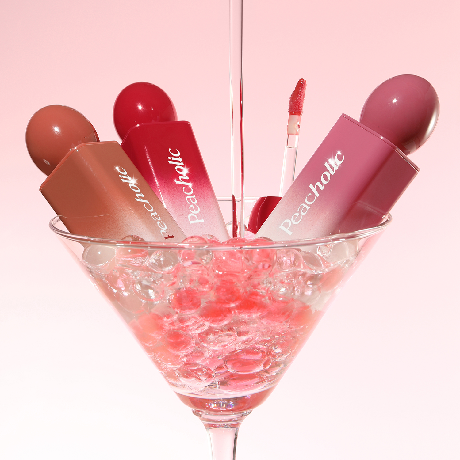 PEACHOLIC Water Glow Lip Tint in various shades displayed in a martini glass with pink and red accents.