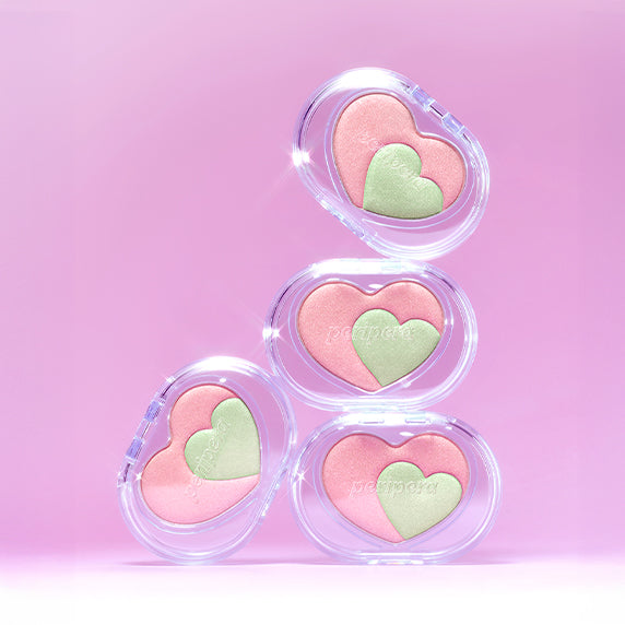 Stacked pink and green heart-shaped PERIPERA Heart Pocket Beam compacts on a pink background.