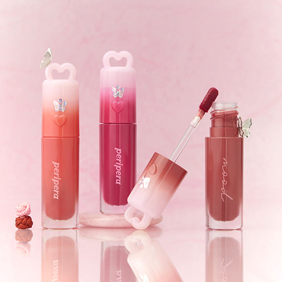 PERIPERA Ink Mood Glowy Tint Princess Hours Collection lip tints in vibrant shades with elegant packaging displayed on pink background.