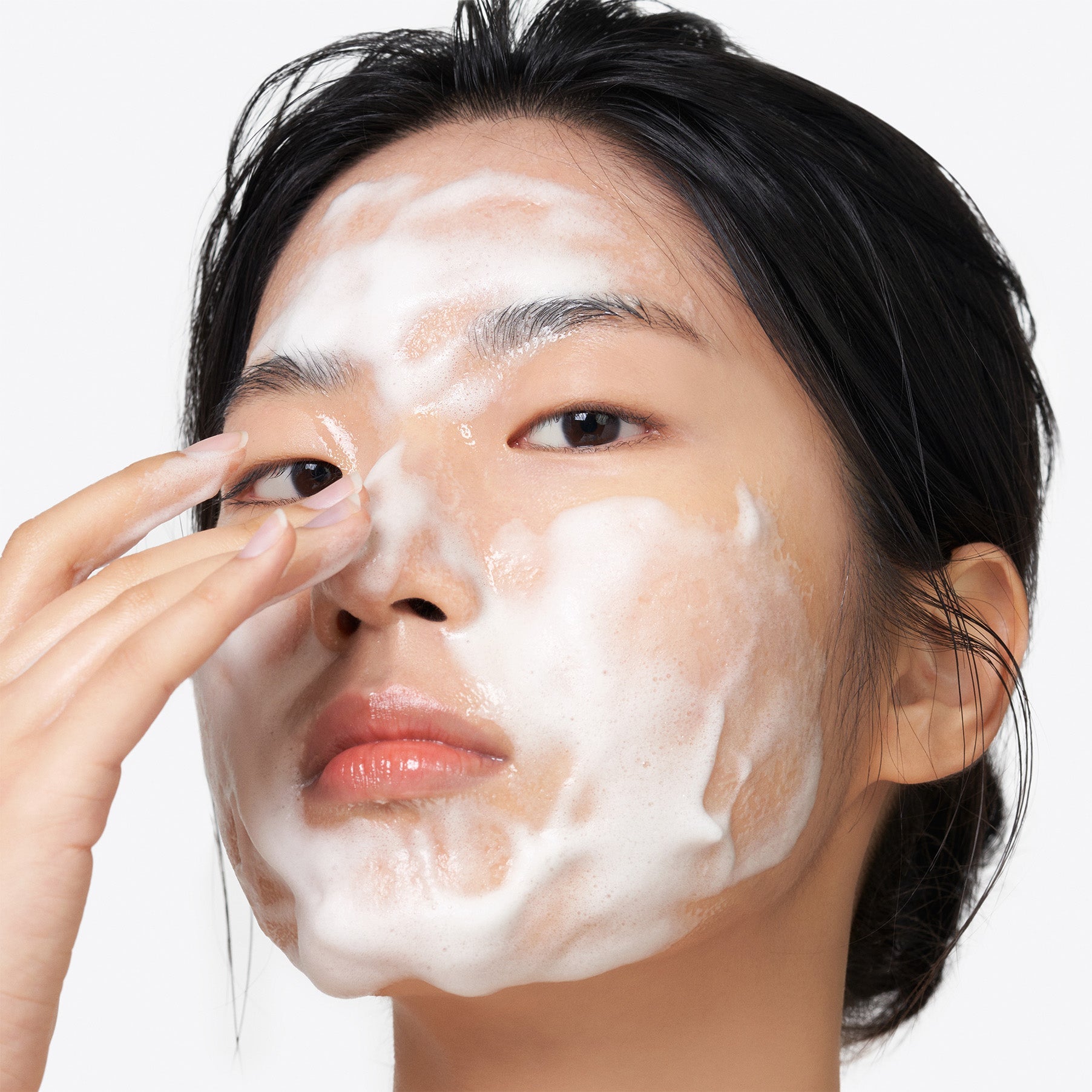 Woman applying PURITO Clear Code Superfruit Cleanser 150ml, demonstrating its foaming texture and skincare benefits.