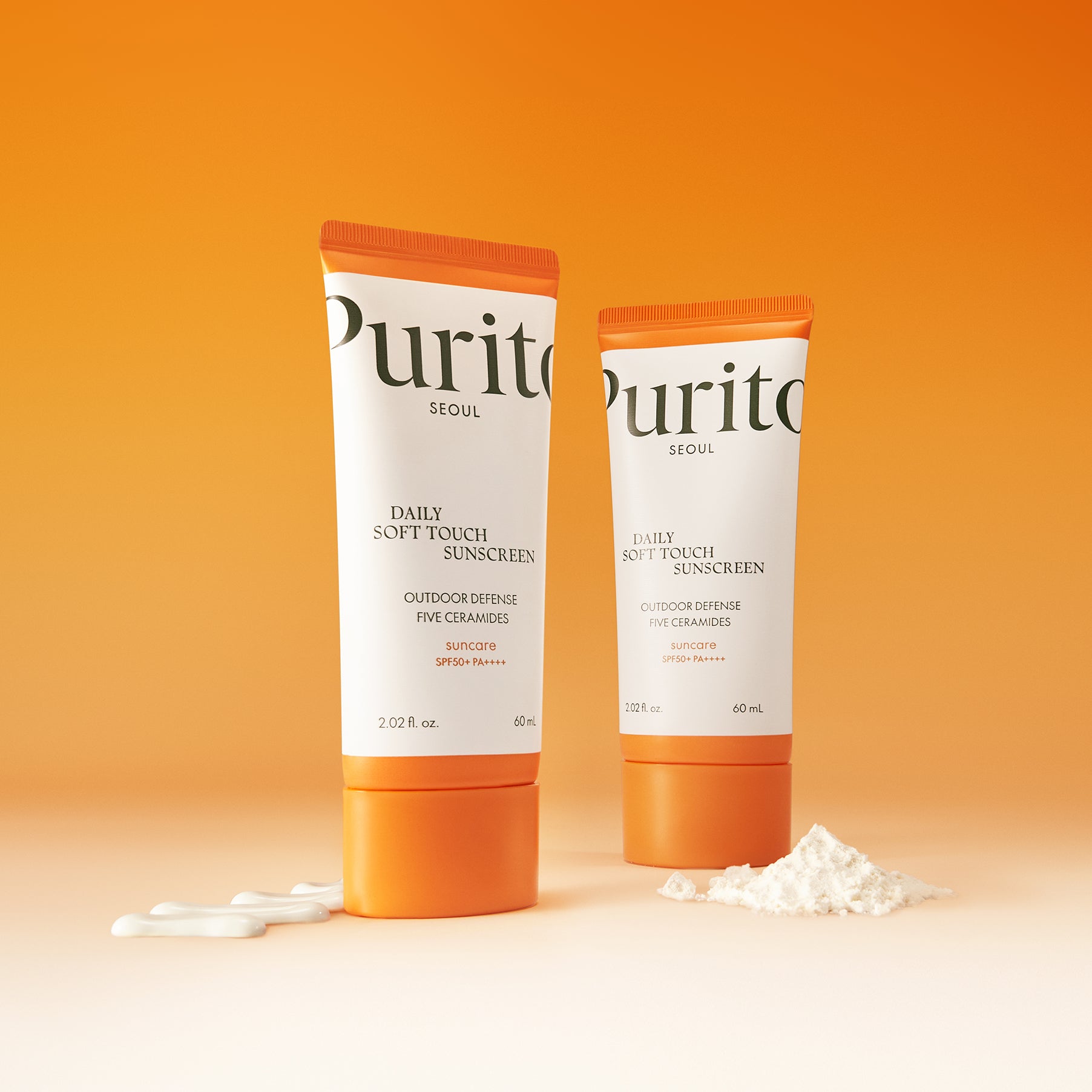 PURITO Daily Soft Touch Sun Cream SPF50+PA++++ tubes on a gradient orange background with cream and powder accents