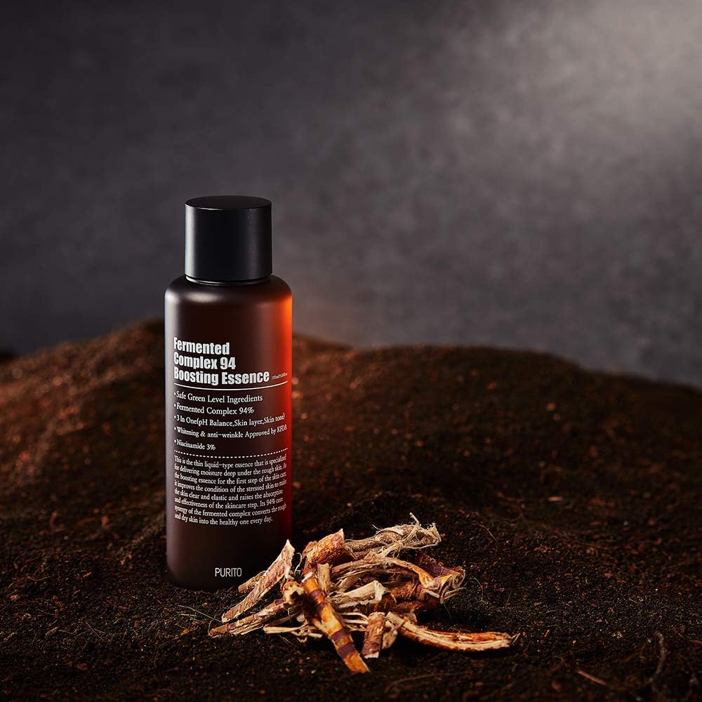 PURITO Fermentedd Complex 94 Boosting Essence 150ml bottle on dark soil background with plant roots.