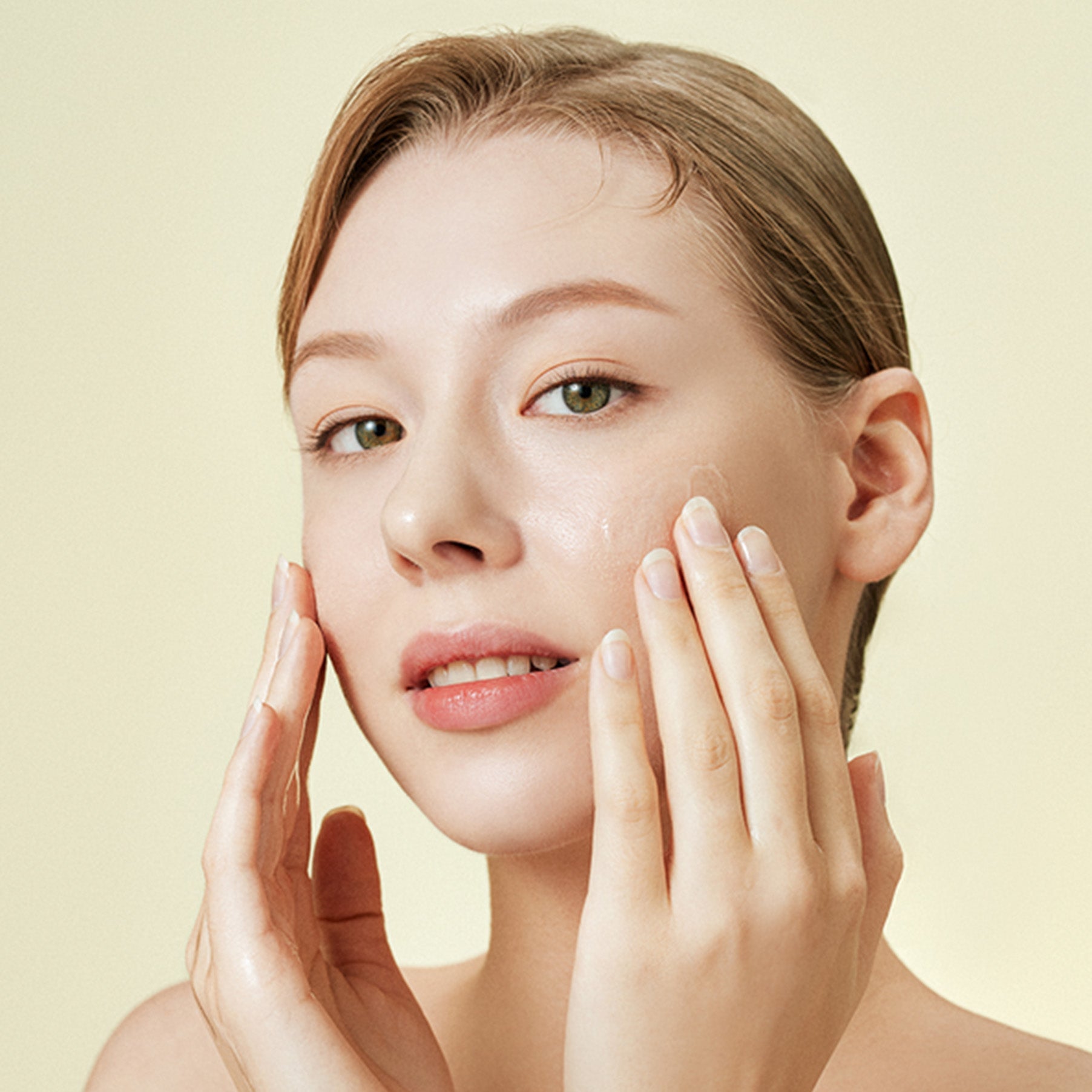 Woman applying skincare product on face, highlighting the benefits of healthy skin care routine and moisturizing techniques.