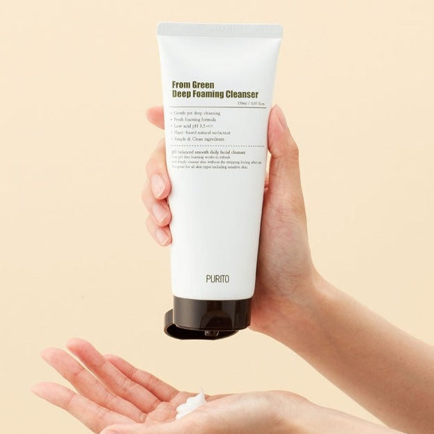 Hands holding PURITO From Green Deep Foaming Cleanser 150ml tube, dispensing product, skincare routine