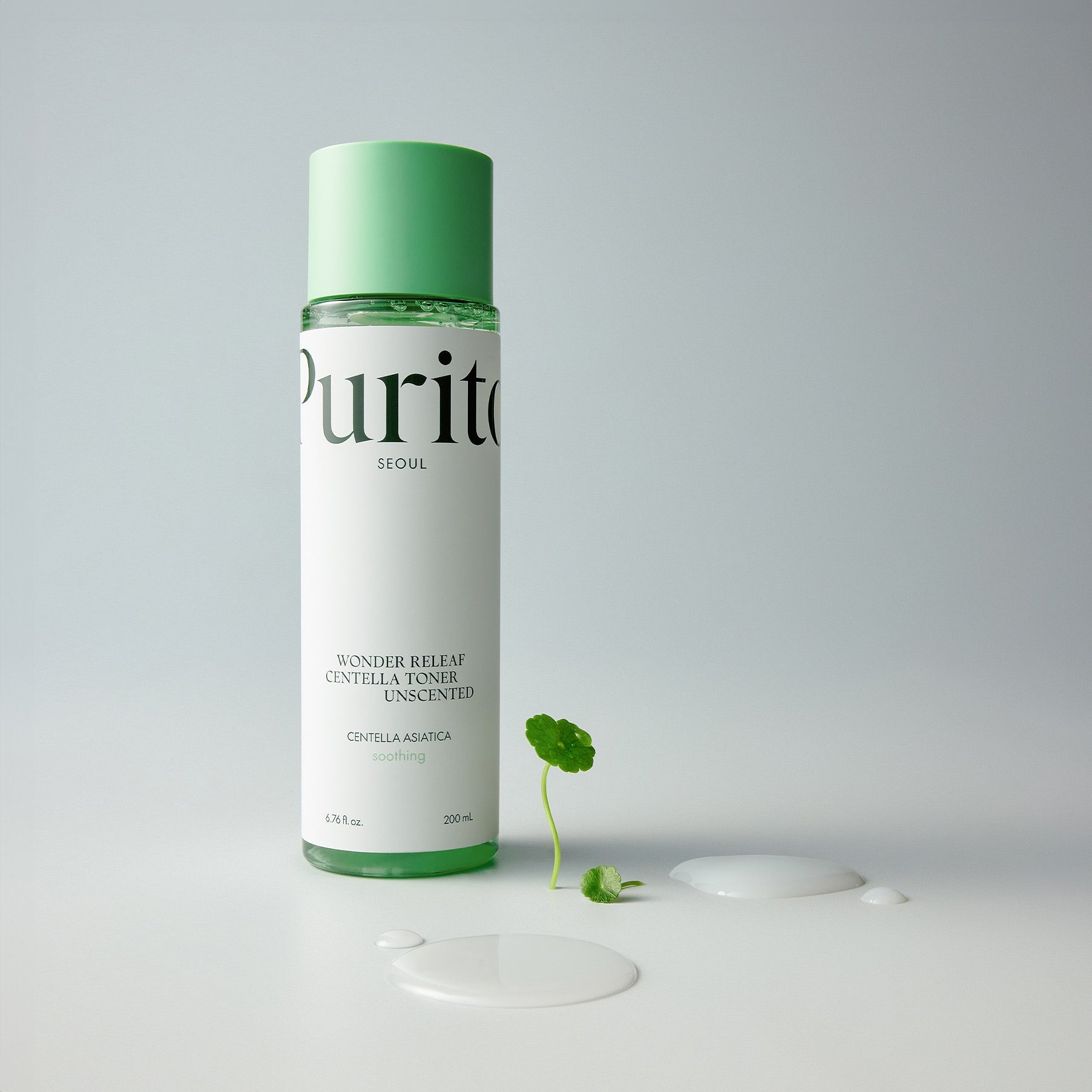 PURITO Wonder Relief Centella Toner Unscented 200ml bottle with centella asiatica leaf and spilled toner beside it.