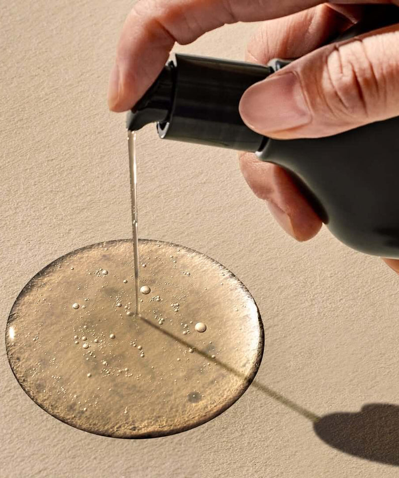 Pouring PYUNKANG YUL Black Tea Boosting Serum 45ml on surface