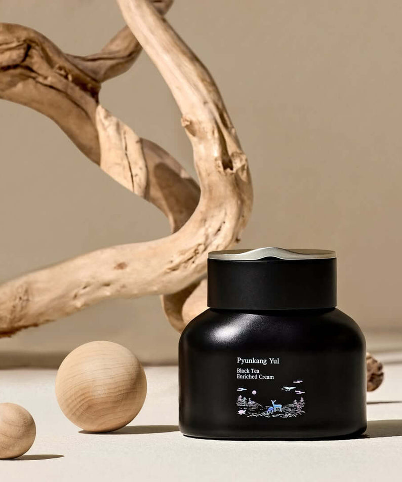 PYUNKANG YUL Black Tea Enriched Cream 60ml in elegant black jar with natural wood accents, luxury skincare product display.