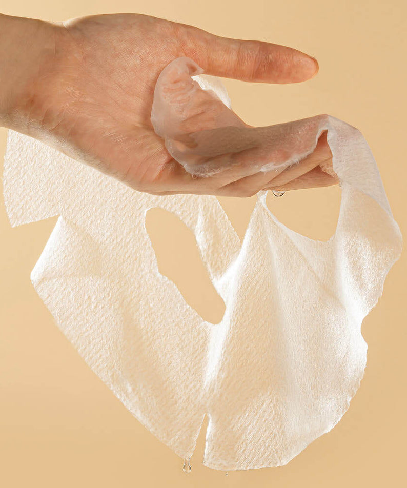 Hand holding a PYUNKANG YUL Brightening Porcelain Skin Mask from the 10 pieces pack, showcasing texture and quality.