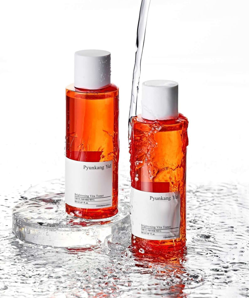 Two bottles of PYUNKANG YUL Brightening Vita Toner 150ml with water splashes.