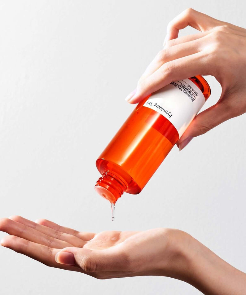 Pouring PYUNKANG YUL Brightening Vita Toner 150ml onto hand for skincare routine.