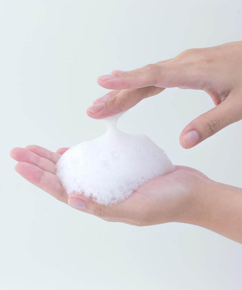 Hands holding foam from PYUNKANG YUL Calming Acne Clear Body Wash 290ml, demonstrating its rich lather and cleansing properties.