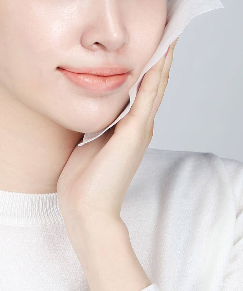 Woman using PYUNKANG YUL Calming Face Towels 80 Pieces on her face for a soft and calm skin care experience.