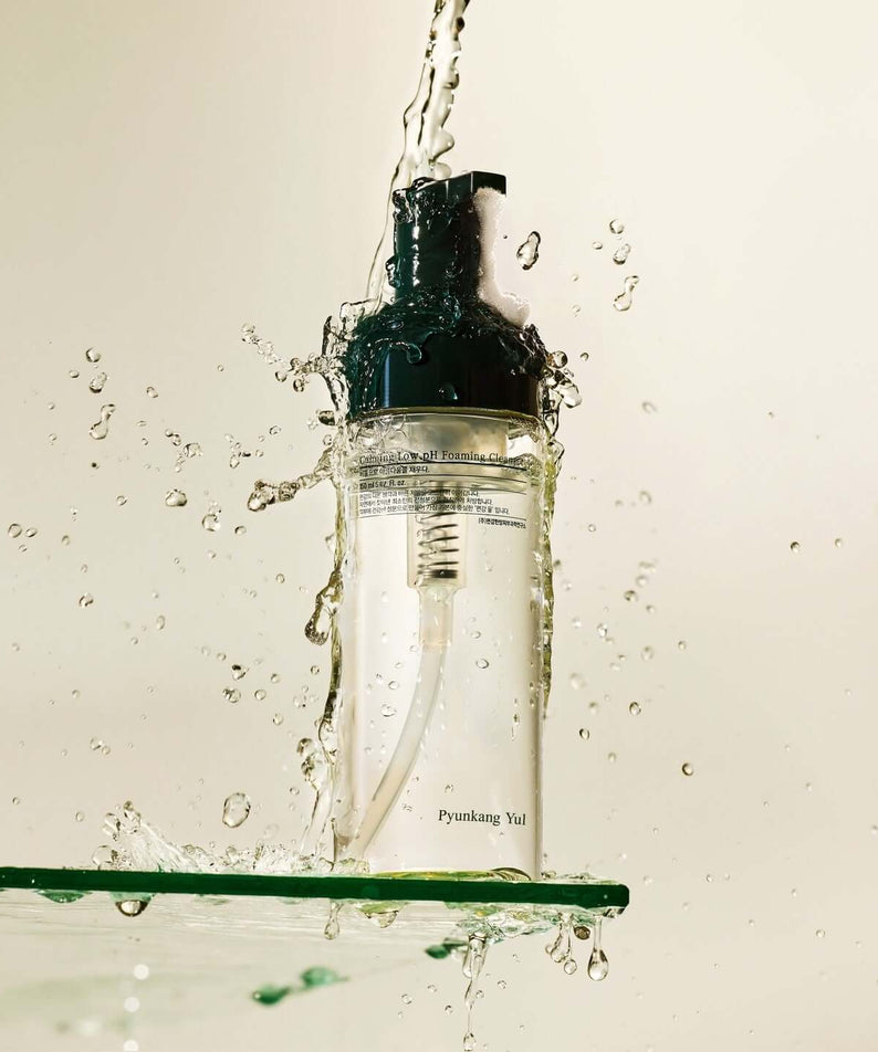 PYUNKANG YUL Calming Low pH Foaming Cleanser 150ml bottle with splashing water, showcasing refreshing skincare product.