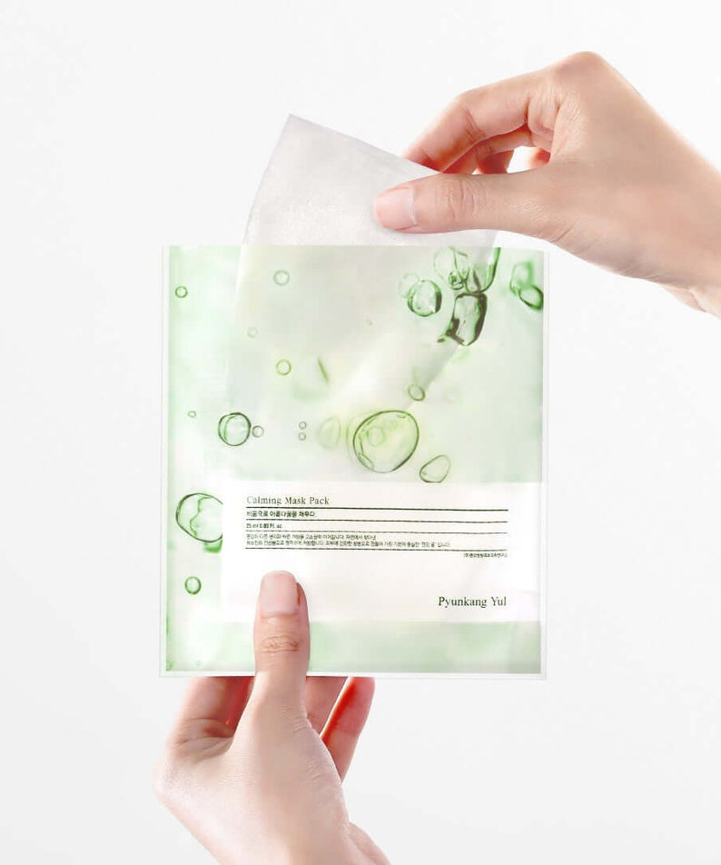 Hands holding a sheet from PYUNKANG YUL Calming Mask Pack 10 Pieces.