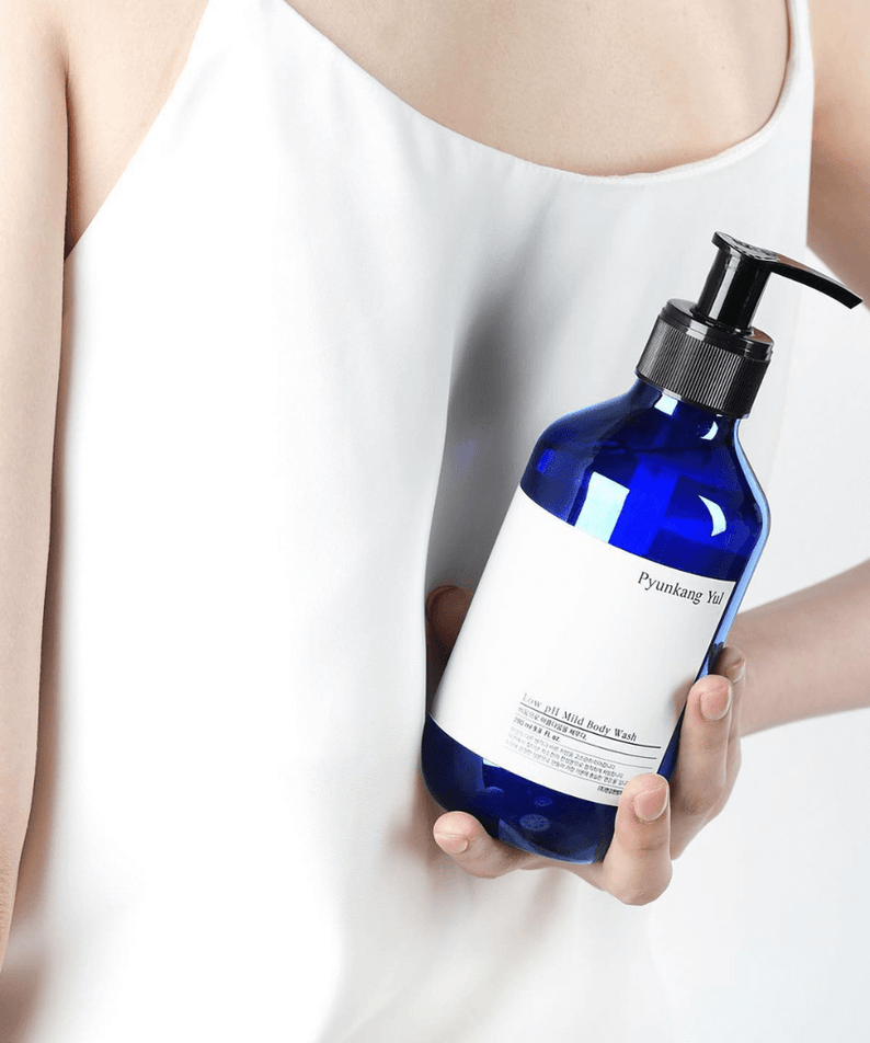 Person holding PYUNKANG YUL Low pH Mild Body Wash 500ml in blue bottle.