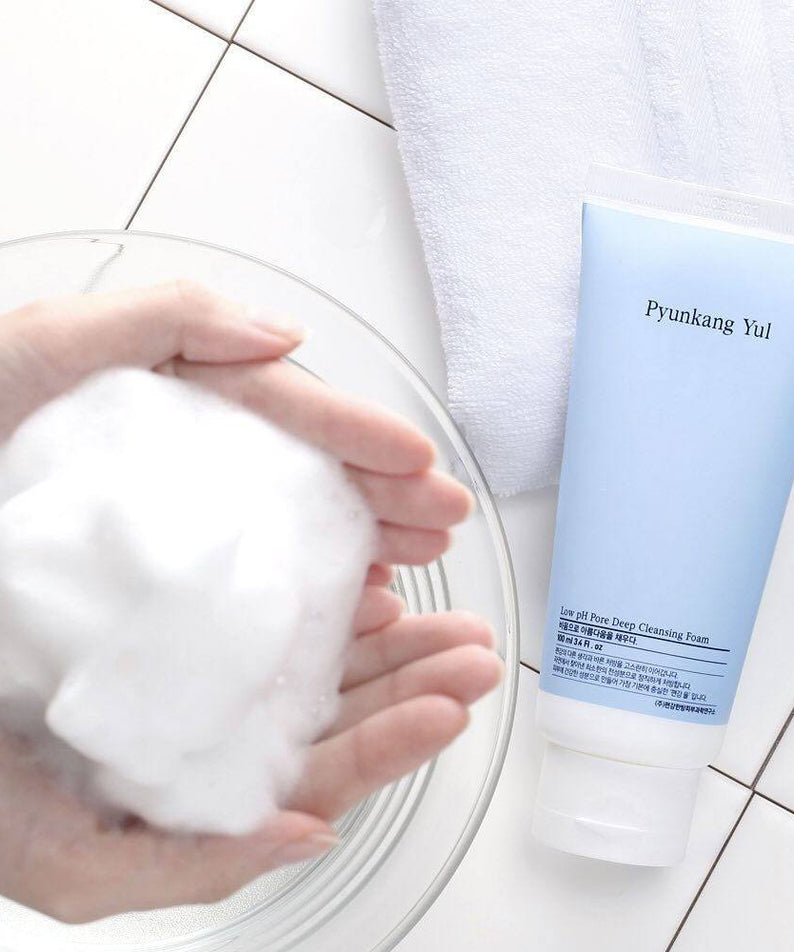 Hands with foam and PYUNKANG YUL Mildly Acidic Pore Deep Cleansing Foam 100ml on a tiled surface