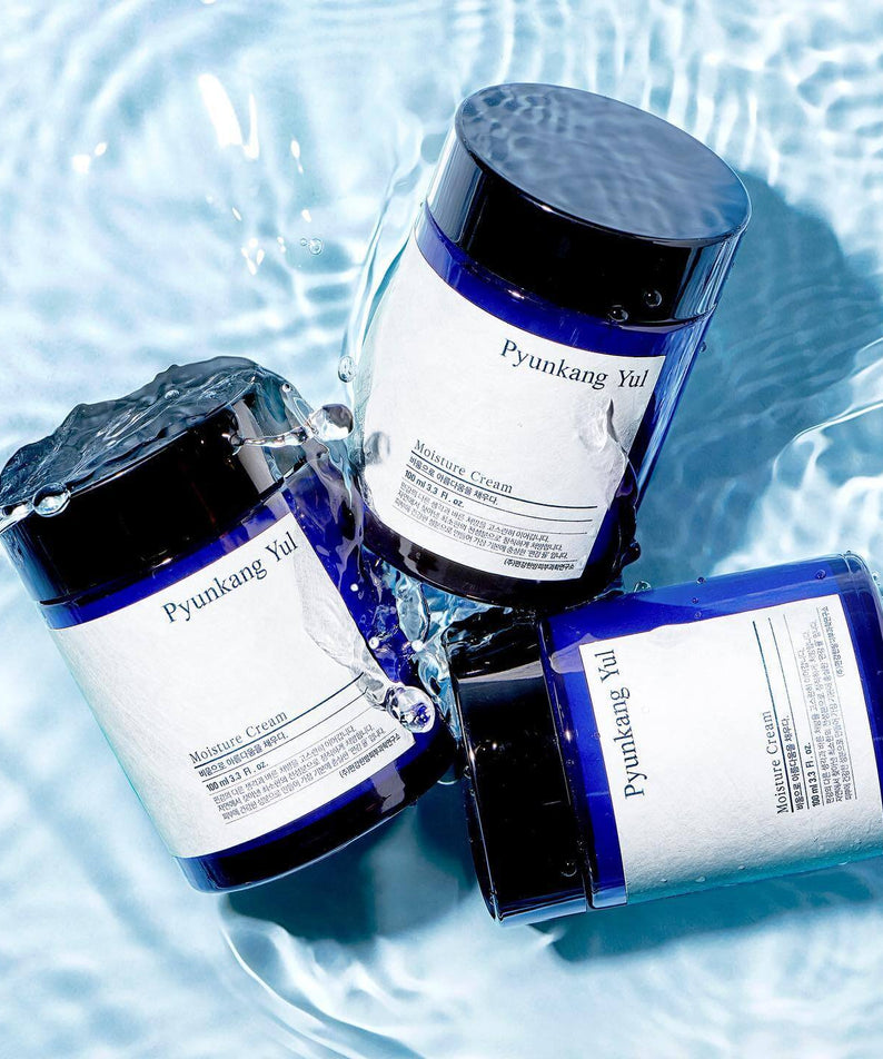 Three jars of PYUNKANG YUL Moisture Cream 100ml floating on water surface