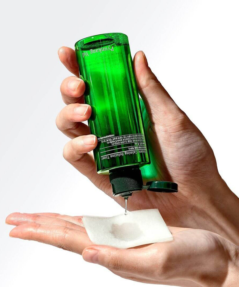 Hands using PYUNKANG YUL Ultimate Soothing Solution Toner 110ml on cotton pad