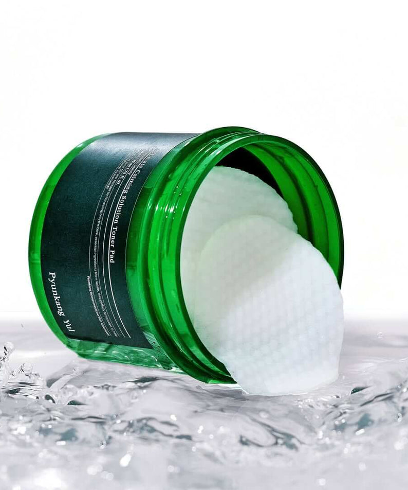 PYUNKANG YUL Ultimate Soothing Solution Toner Pads 70 sheets 140ml in a green jar on a wet surface.