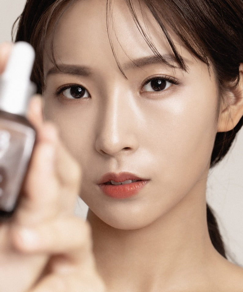 Woman holding a bottle of QUA-T Dia Nano Emulsion Full Cica Soothing Ampoule 30ml