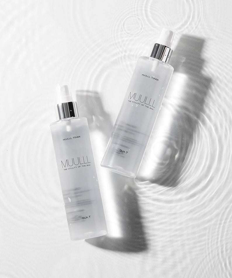 QUA-T Toner 200ml bottles placed on a rippled water surface, showcasing premium skincare packaging.